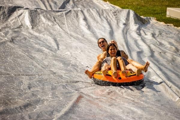 Two people in an inner tube sliding down a hill.